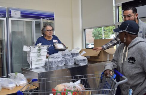 a volunteers offers a prepared meal to a pantry guest