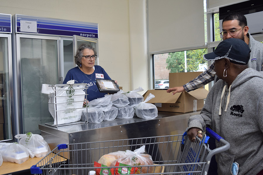 a volunteers offers a prepared meal to a pantry guest