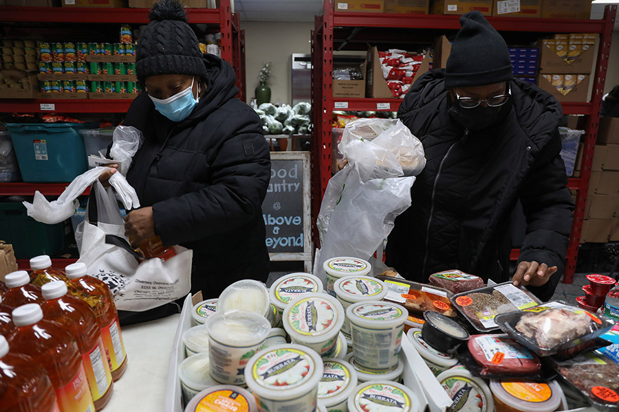 Dos mujeres seleccionan artículos en una despensa de alimentos.